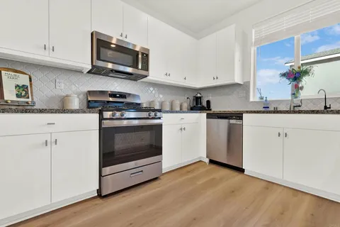 a kitchen with granite countertop a stove top oven sink and cabinets