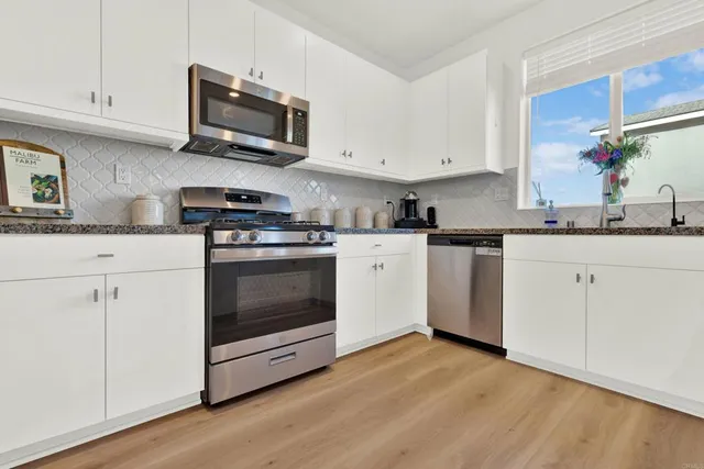 a kitchen with granite countertop a stove top oven sink and cabinets