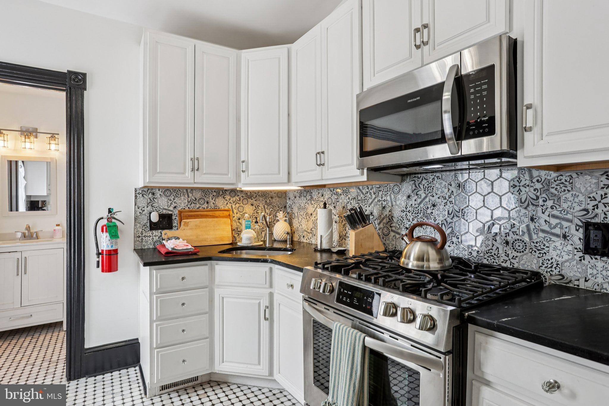414 Broadway Cape May, NJ 08204 - Photo 35 of 48 a kitchen with stainless steel appliances a stove a microwave and cabinets