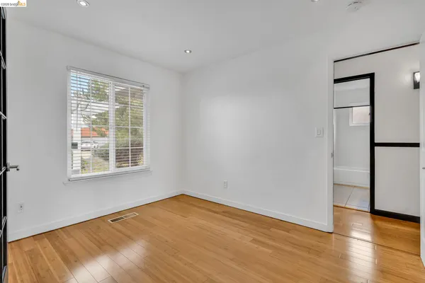a view of an empty room with window and wooden floor