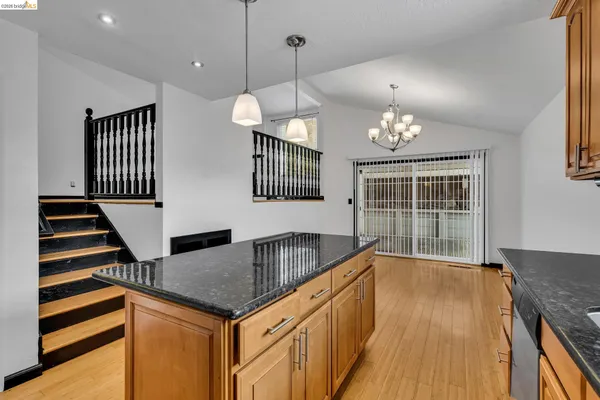 a kitchen with stainless steel appliances granite countertop a stove a sink dishwasher a refrigerator and a dining table with wooden floor