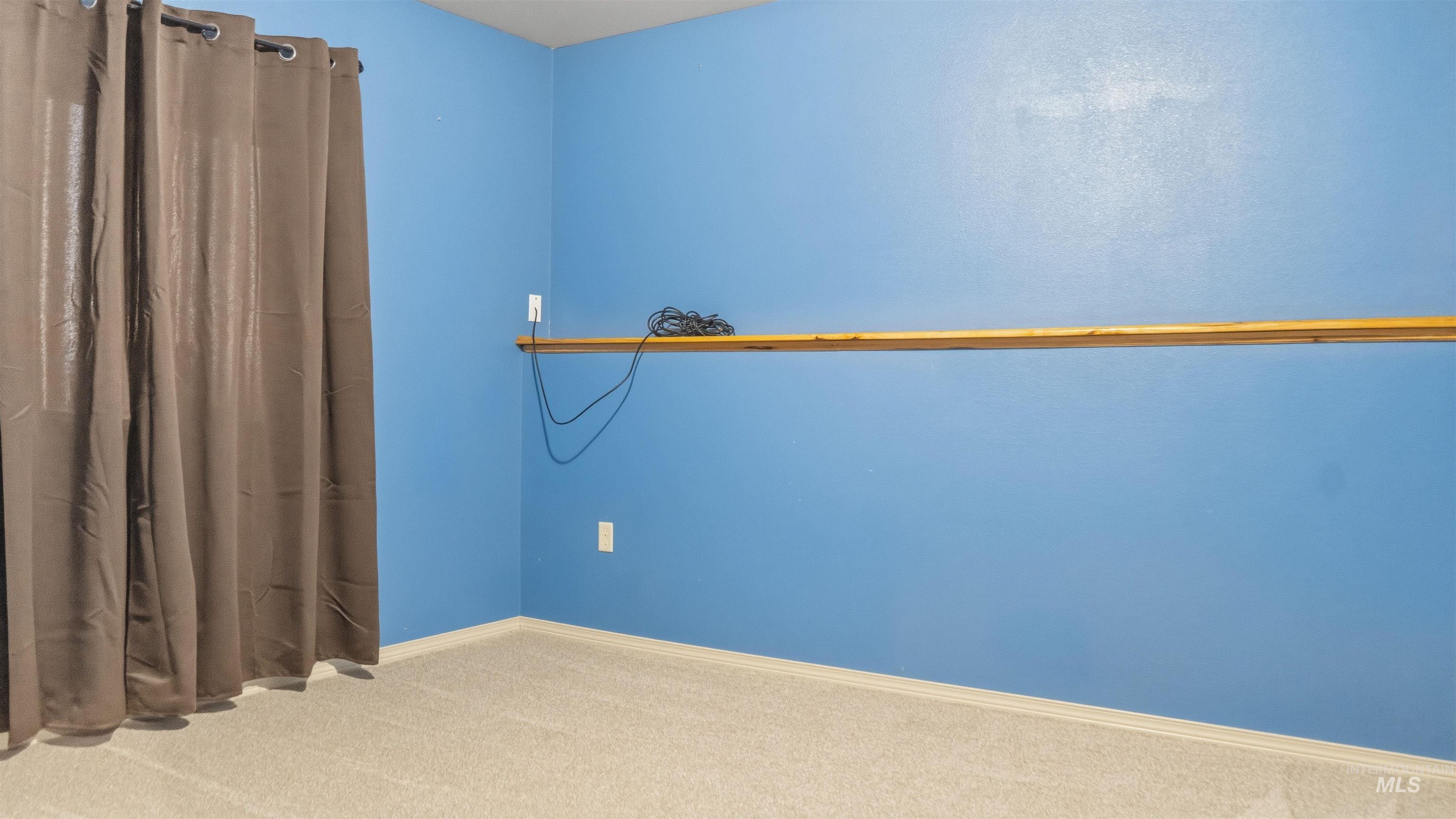 1028 Granlund Road Troy, ID 83871 - Photo 25 of 35 Carpeted room featuring blue painted walls, a built-in wood shelf, and a window with curtain rod - Basement