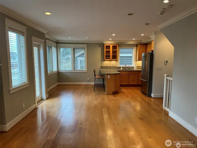 a living room with stainless steel appliances granite countertop furniture wooden floor and a window