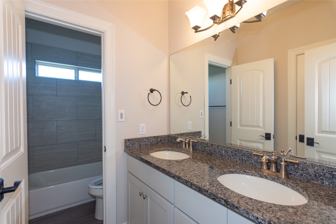 316 Chadwick Drive Georgetown, TX 78628 - Photo 24 of 39 a bathroom with a granite countertop sink a toilet a mirror and shower