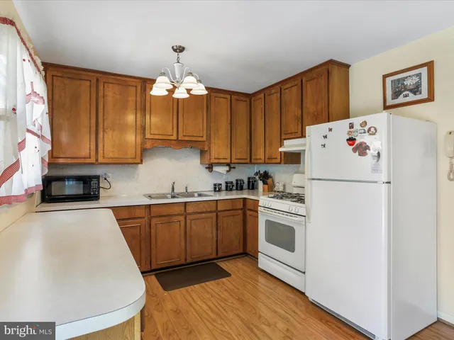a kitchen with a white refrigerator stove a sink and dishwasher with wooden floor