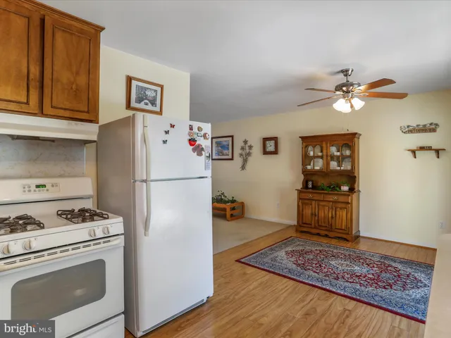 a kitchen with stainless steel appliances kitchen island granite countertop a refrigerator a stove a microwave oven with white cabinets and wooden floor