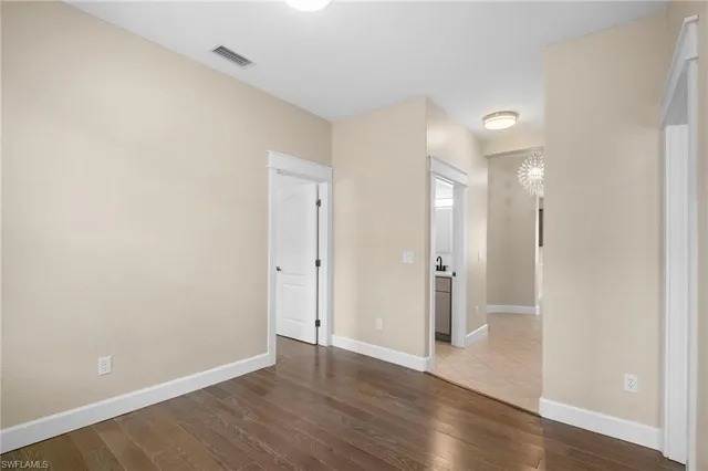 a view of an empty room with wooden floor and a bathroom