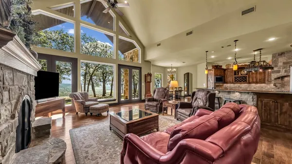 a living room with furniture a flat screen tv and floor to ceiling window