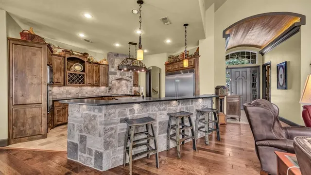 a large kitchen with stainless steel appliances kitchen island granite countertop a table chairs in it and wooden floors
