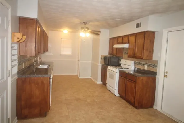 a kitchen with stainless steel appliances granite countertop a stove a sink and a refrigerator