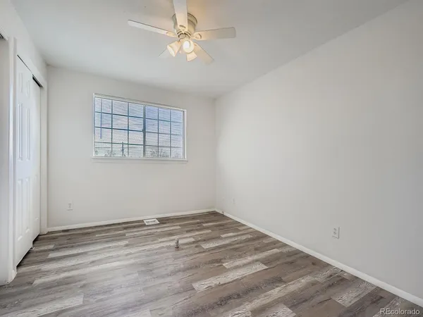 an empty room with wooden floor fan and windows