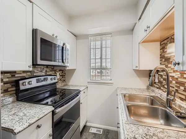 a kitchen with granite countertop a sink stove and cabinets