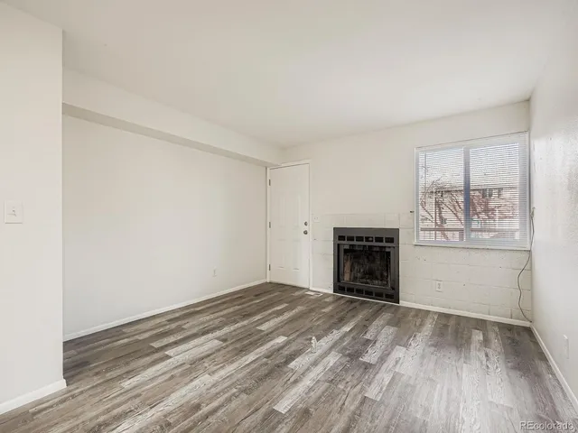 an empty room with windows and fireplace