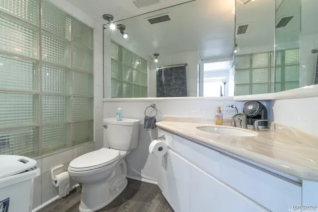 a bathroom with a granite countertop toilet a sink and a large mirror