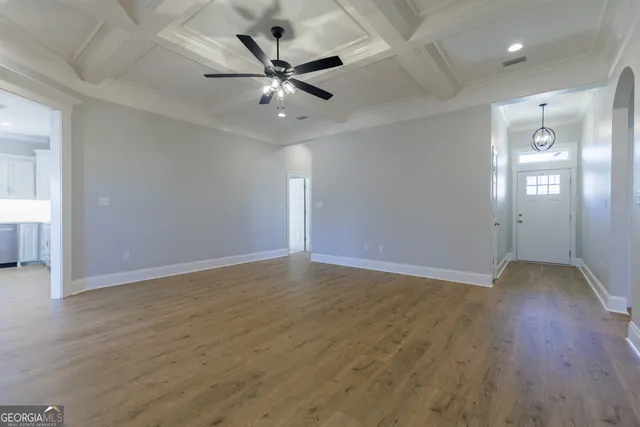 an empty room with wooden floor and ceiling fan