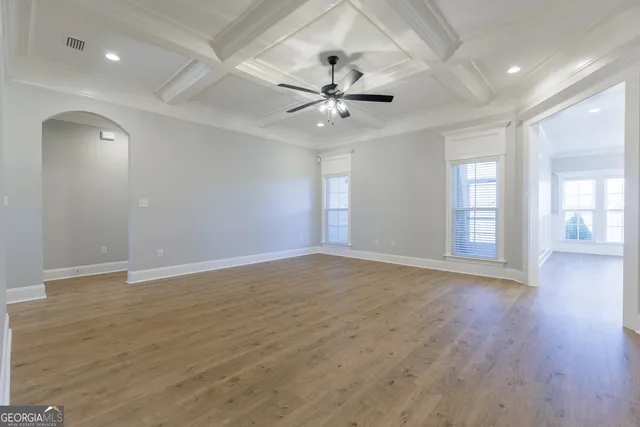 a view of an empty room with window and wooden floor