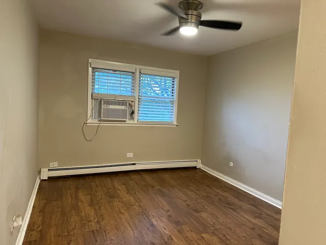 an empty room with wooden floor fan and windows