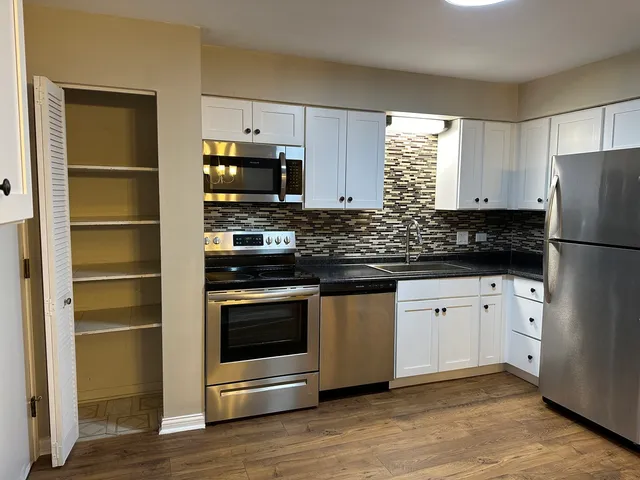 a kitchen with granite countertop a refrigerator stove and sink