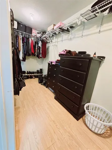 a view of walk in closet with clothes and shoes