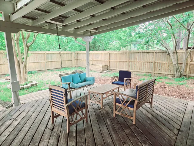 a patio with wooden floor a yard a table and chairs