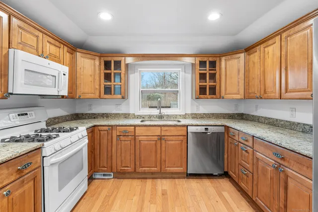 a kitchen with stainless steel appliances granite countertop wooden cabinets a sink and dishwasher a stove with wooden floor