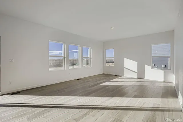 a view of an empty room with window and wooden floor