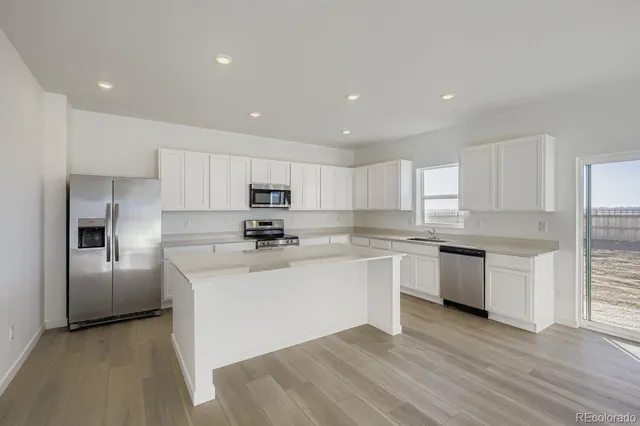 an open kitchen with white cabinets and stainless steel appliances