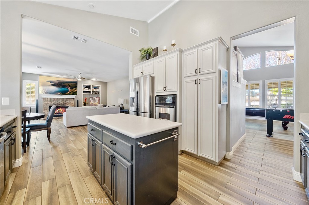 36232 Village Road Yucaipa, CA 92399 - Photo 13 of 34 a kitchen with stainless steel appliances a stove a refrigerator a dining table and chairs with wooden floor