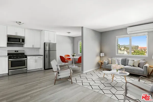 a living room with furniture a flat screen tv and a refrigerator