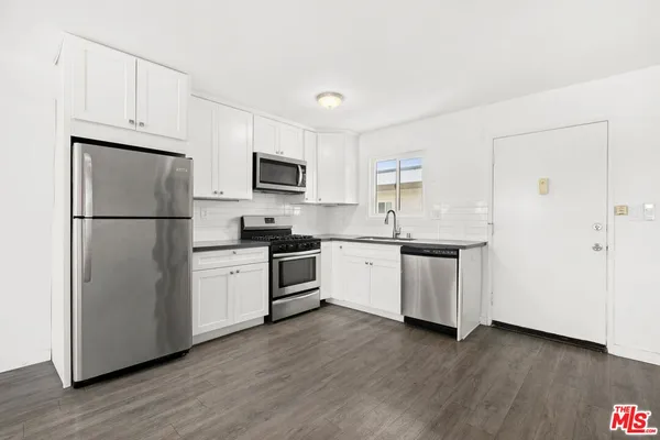 a kitchen with a refrigerator stove and white cabinets