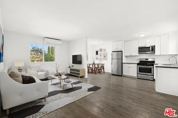 a living room with furniture a flat screen tv and kitchen view