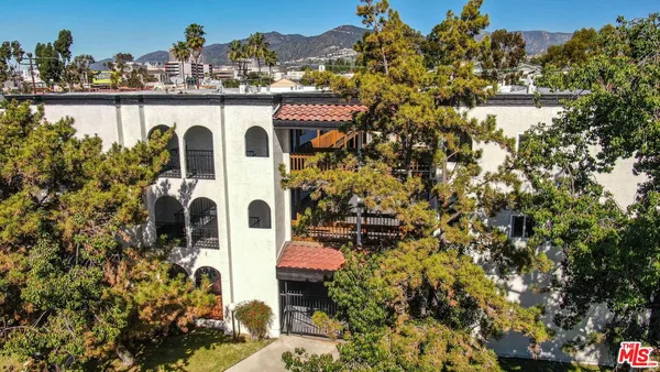 a view of a white house with a big yard and large trees