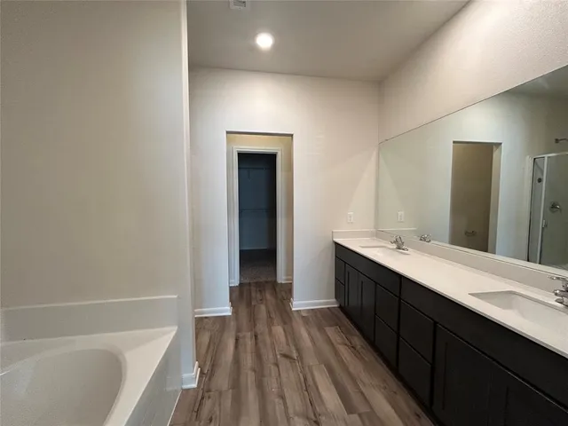 a bathroom with a double vanity sink a mirror and a bathtub