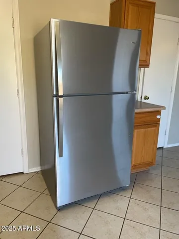 a view of a refrigerator in kitchen and an empty room