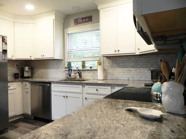 a kitchen with granite countertop a sink a stove a microwave and cabinets