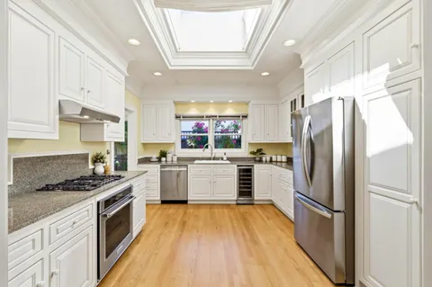 a kitchen with a refrigerator a sink dishwasher a stove and white cabinets with wooden floor