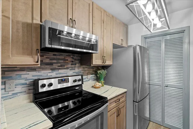 a kitchen with stainless steel appliances granite countertop a stove a refrigerator and a microwave