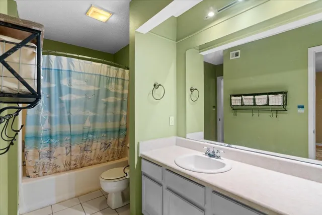 a bathroom with a granite countertop sink a toilet a mirror and shower