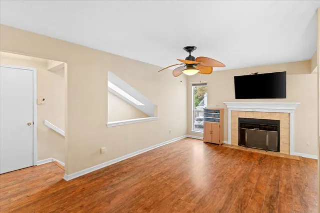 a view of a livingroom with a fireplace a ceiling fan and windows