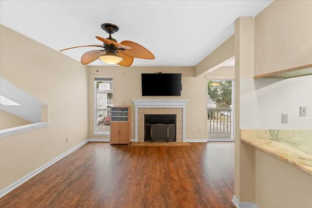 a view of a livingroom with a fireplace a ceiling fan and wooden floor