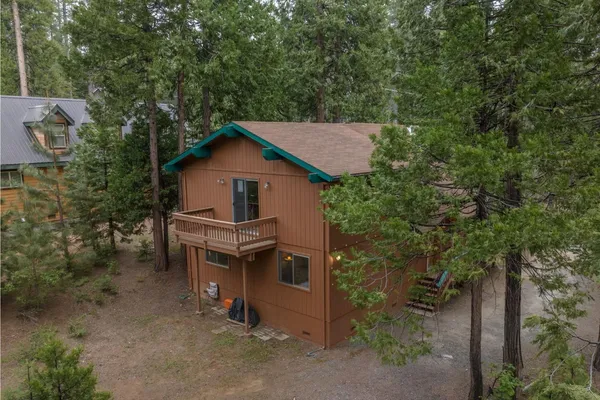 an aerial view of a house with a yard and trees all around