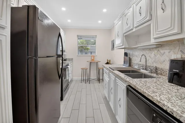 a kitchen with stainless steel appliances granite countertop a refrigerator a sink a stove and dishwasher
