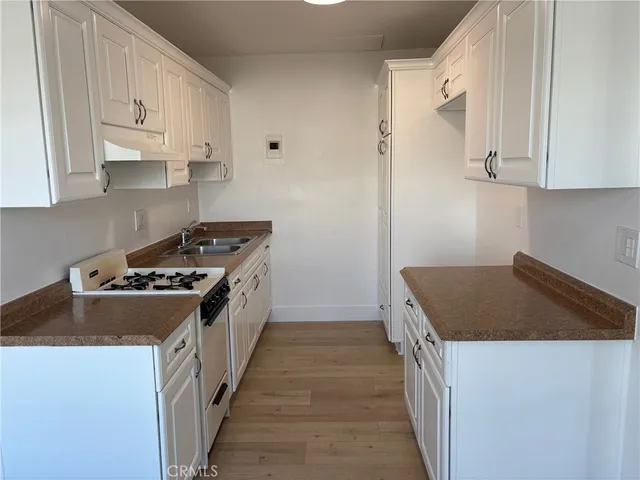 a kitchen with granite countertop a stove and a white cabinets