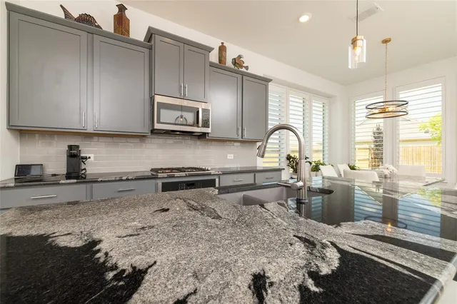 a kitchen with stainless steel appliances granite countertop a sink a stove a refrigerator and chairs