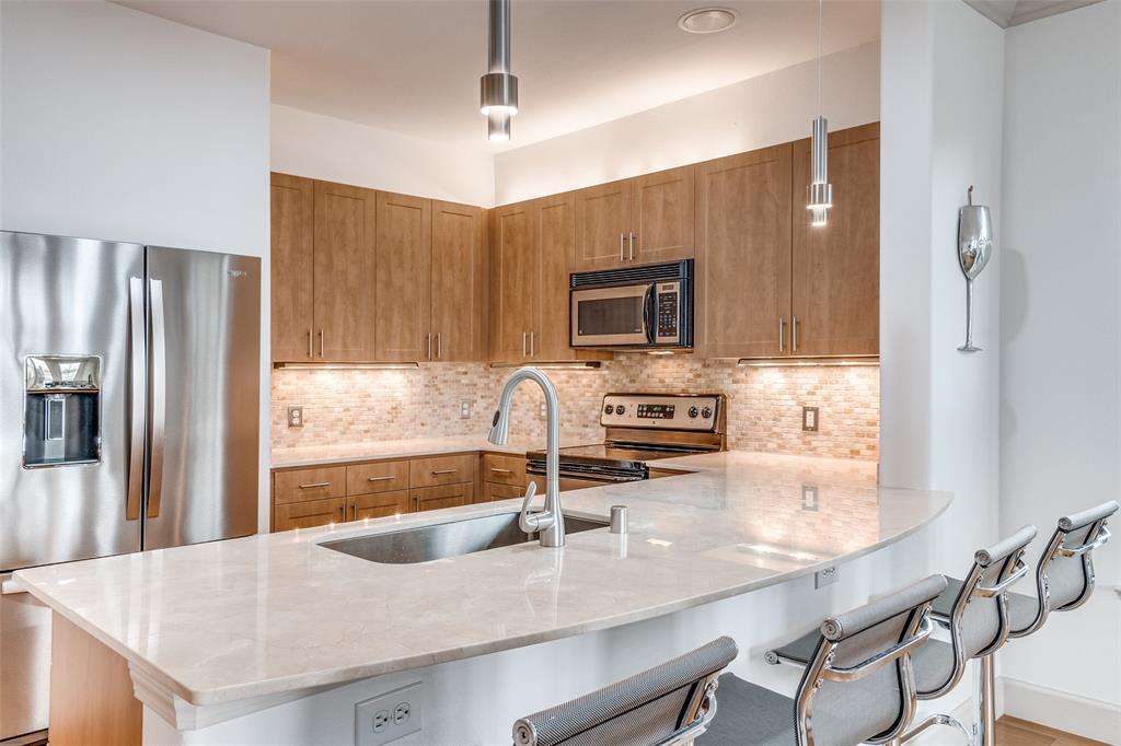 3818 Holland Avenue, Unit 309 Dallas, TX 75219 - Photo 5 of 24 a kitchen with kitchen island granite countertop a sink stove and refrigerator