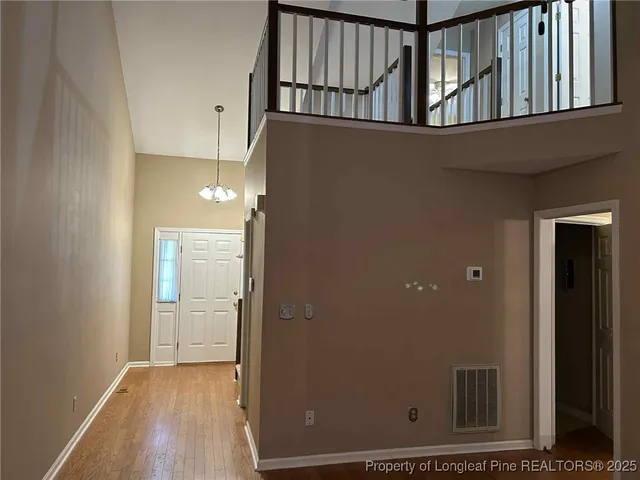 an empty room with wooden floor fireplace and windows