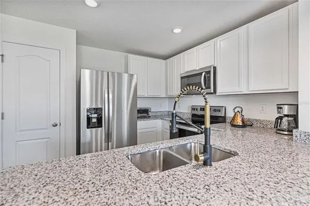 a kitchen with stainless steel appliances granite countertop a refrigerator sink and stove