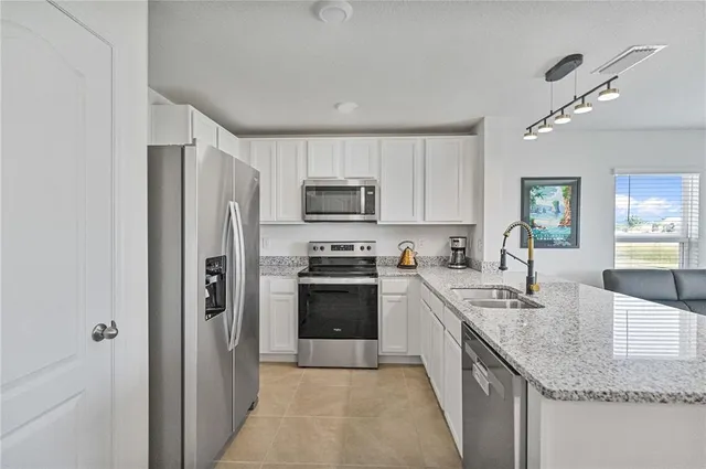 a kitchen with granite countertop a refrigerator stove and sink