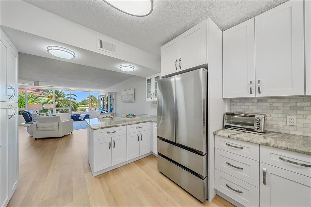 100 Sands Point Road, Unit 225 Longboat Key, FL 34228 - Photo 28 of 41 a kitchen with stainless steel appliances a refrigerator a stove a sink dishwasher and white cabinets with wooden floor