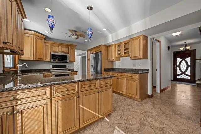 a kitchen with stainless steel appliances granite countertop a refrigerator a sink dishwasher and white cabinets with wooden floor